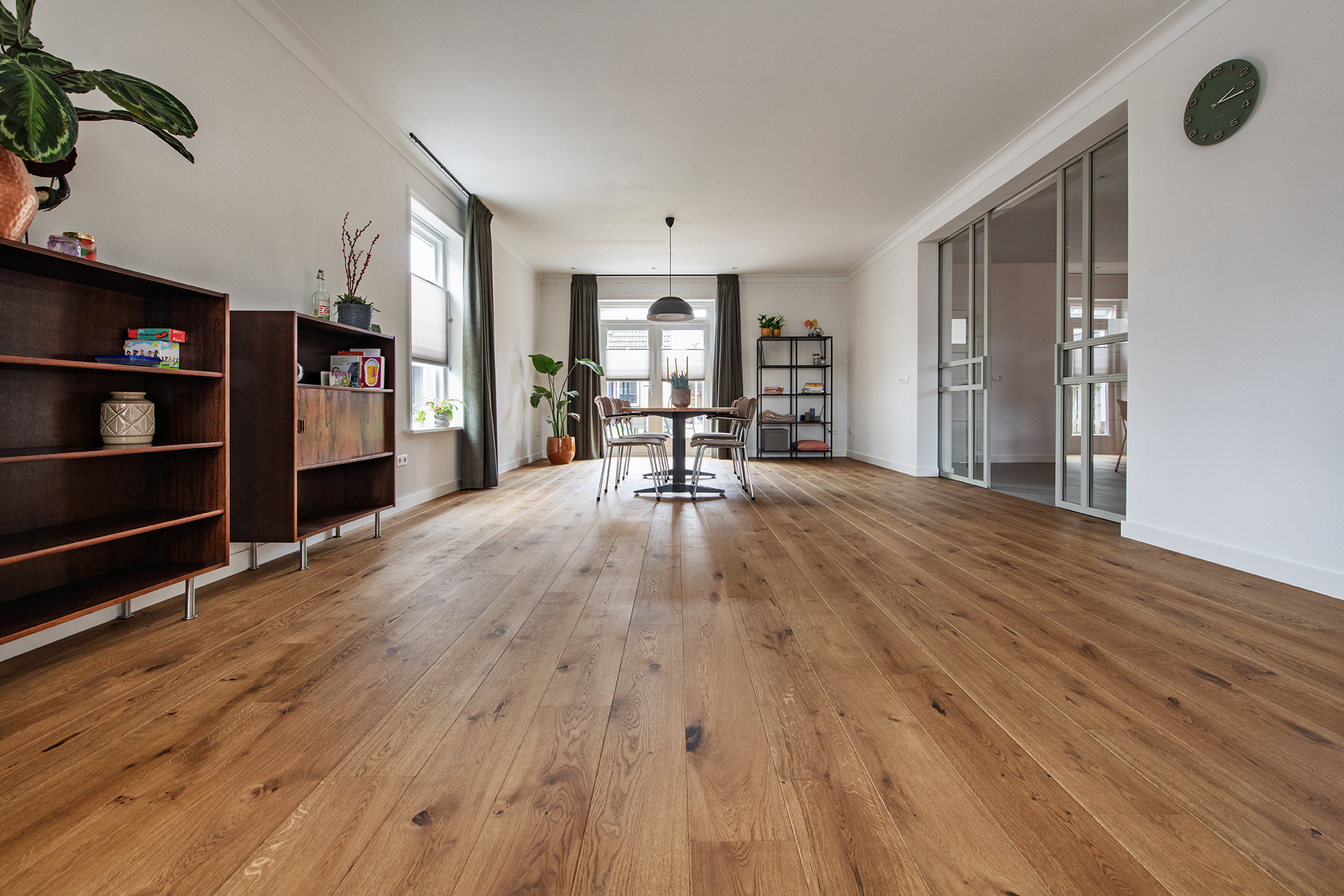 Rustiek eiken parketvloer in stroken gelegd op vloerverwarming in woonkamer met stalen deuren